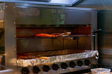 Freshly grilled barbecue dishes at a restaurant, featuring zucchini, baby corn, pork ribs, and juicy chicken steak sizzling on the grill