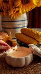 Cozy autumn scene with candle, corn, and sunflowers