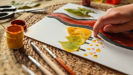 Artistic autumn leaf painting with hand