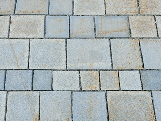 Obraz premium Granite pavement with rough texture, varying gray tones, and natural discoloration. Close-up. Copyspace.