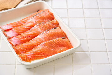 生鮭の切り身｜白バットに並べた料理素材（タイル背景）