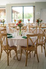 A beautifully decorated wedding or celebration event table with colorful flowers, vintage plates, and cutlery in soft natural light.The space blends modern, rustic,retro elements with charming chairs.