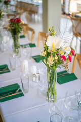 A beautifully decorated wedding or celebration event table with colorful flowers, vintage plates, and cutlery in soft natural light.The space blends modern, rustic,retro elements with charming chairs.