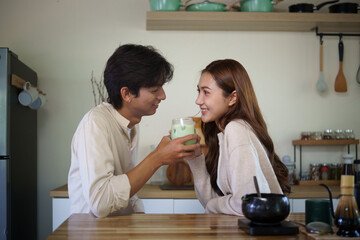 Romantic young couple enjoying a glass of matcha latte together in a cozy kitchen.