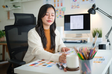 Female web designer developing mobile app layout, reviewing user interface mockups and design plans.