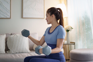 Fit woman practicing dumbbell exercises indoors, maintaining health and wellness with home workout routine.