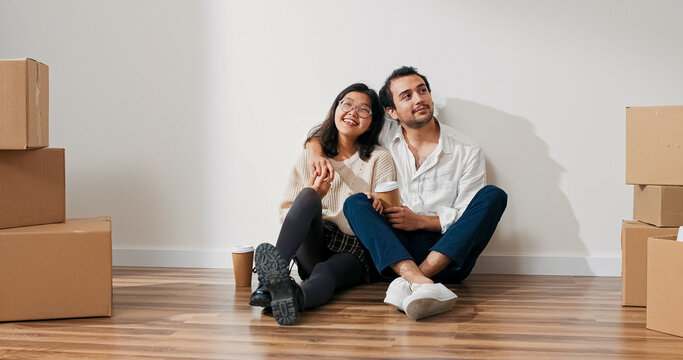 A couple enjoys coffee together in their new apartment. They sit by the wall, discussing appliances, colors, and future flat arrangements.