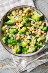 Broccoli, chickpea, avocado salad, a healthy and filling snack, close-up, in a bowl on the table. Vertical top view from above