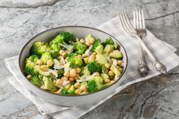 close-up of a dietary salad of broccoli, chickpeas, avocado, onion, and parsley in a bowl on a table. Horizontal