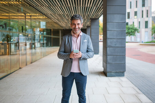 Mature man smiling using phone in urban setting