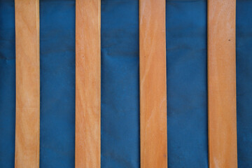 A view from above shows several narrow flat wooden pieces These are spaced evenly across a blue surface and run vertically within the frame