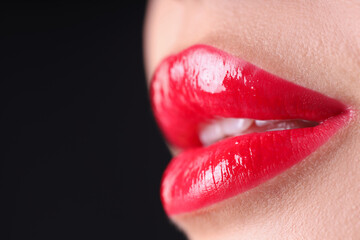 Woman with beautiful red lipstick on her lips against black background, macro view. Space for text