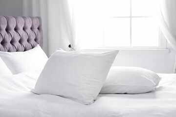 Modern bed with soft pillows near window