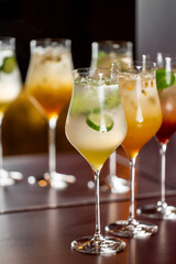 Assorted colorful cocktails in elegant glasses with garnishes like lime and mint, arranged on a reflective surface. Blurred background. Ideal for mixology, bar, or party themes.