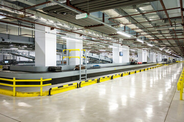 Obraz premium Modern airport baggage handling area with conveyor belts and luggage carts.
