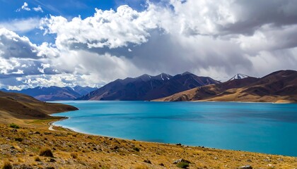 Fototapeta premium Scenic view of a blue lake surrounded by mountains under a cloudy sky