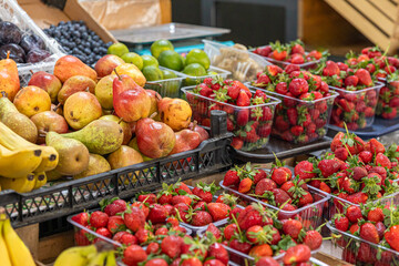Fresh and ripe strawberries, pears, blueberries, limes and other various organic fruits and berries at the market counter. Healthy natural food concept