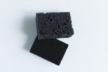 Two gray dishwashing sponges. Porous and abrasive sides. White background.