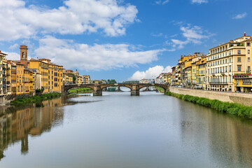 View of the of Arno River with Santa Trinita Bridge and Florence's stunning architecture the banks and a clear blue sky above