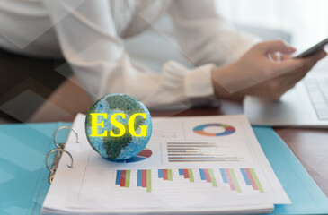 ESG on globe and Investor read report of company on environmental stewardship and social relations management, including governance.