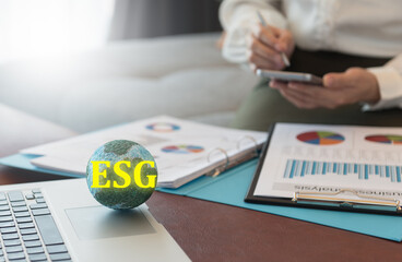 ESG on globe and Investor read report of company on environmental stewardship and social relations management, including governance.