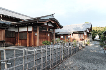 Naklejka premium Weathered Traditional Japanese Wooden House (Kominka) with Overgrown Greenery and Tile Roof