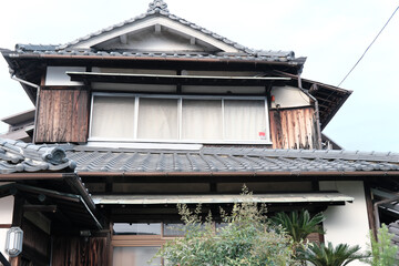 Weathered Traditional Japanese Wooden House (Kominka) with Overgrown Greenery and Tile Roof