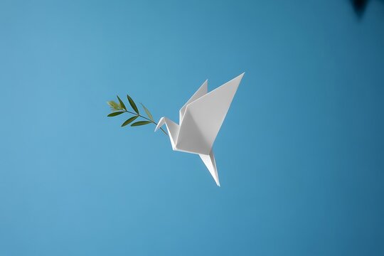 Elegant origami peace dove with fresh green olive branch soaring through clear blue sky, symbolizing hope and serenity for global harmony