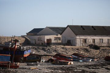 Small boats resting on beach sand with buildings in the background