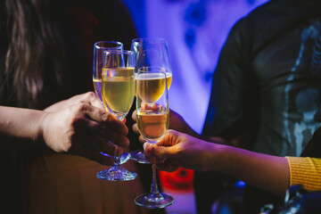 Close-up of people toasting with glasses of champagne or wine, celebrating together at a festive party with joyful atmosphere.