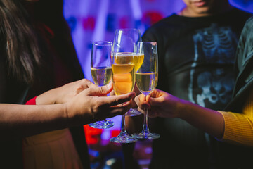 Close-up of people toasting with glasses of champagne or wine, celebrating together at a festive party with joyful atmosphere.