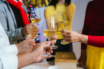 Group of friends clinking glasses of champagne together at a festive party, celebrating happiness and friendship with joyful smiles.