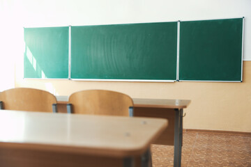 Desks with chairs and green chalkboard in classroom