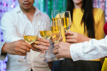 Group of friends wearing Santa hats raising glasses of champagne, celebrating Christmas or New Year together with joy and smiles.