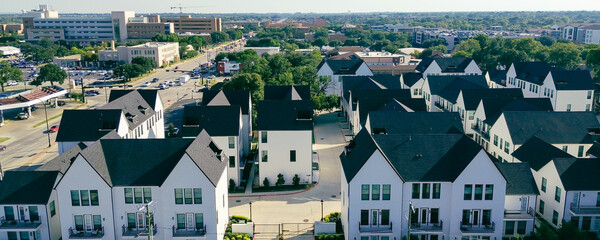 Panorama aerial view busy Cooper Street in downtown Arlington, Texas during peak hour. New development townhomes, retail stores, and campus building with crane, transit-integrated urban corridor
