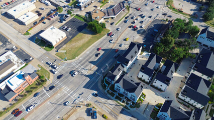Flat-roof retail buildings and busy outdoor parking lot near Cooper, Abram and Main Street intersection in downtown Arlington, Texas. Adjacent townhomes and visible traffic mixed-use planning