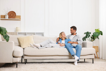 Happy couple spending time together on sofa at home. Space for text