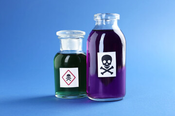 Bottles of poison with warning signs on light blue background, closeup