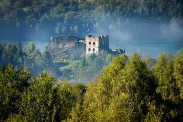 Ruins of medieval castle on the top of Castle Hill in Czorsztyn. Lesser Poland Voivodeship, in the Pieniny Mountains, on Lake Czorsztyn. Morning rays of sunshine, the castle shrouded in fog