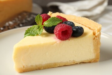 Piece of delicious cheesecake with fresh berries and mint on table, closeup