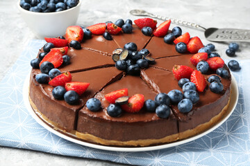 Tasty chocolate cheesecake with berries on light grey textured table, closeup