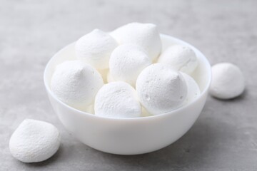 Yummy meringue cookies in bowl on grey table, closeup