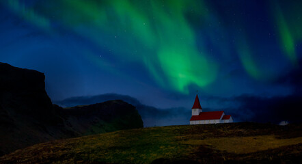 Amazing view of aurora northern light with red church in vik , iceland.