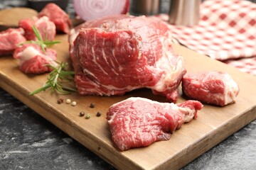 Pieces of raw beef meat and spices on black marble table, closeup