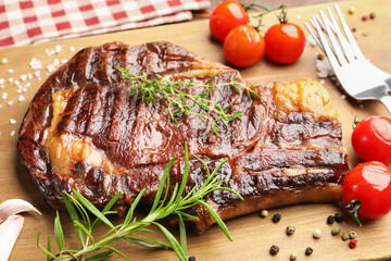 Delicious grilled beef steak with herbs, spices and products on wooden board, closeup