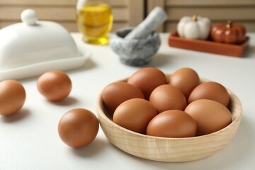 Raw chicken eggs in bowl on white table, closeup