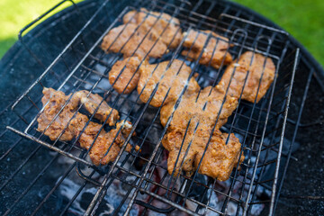 A marinated pork steak is grilling on a charcoal barbecue grill, with visgrill marks and smoke....