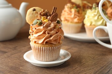 Delicious cupcakes with colorful cream and decor on wooden table, closeup. Space for text