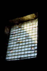 Glass block window illuminated by light in a dark room.