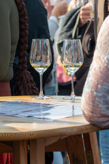 Two glasses of white wine stand on a wooden table at a busy wine festival in Retz, Austria.